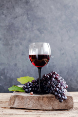 A glass of red wine on black background with bunch of grapes