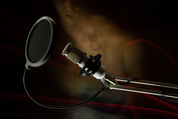 Professional condenser studio microphone on the black background and freezelight and faces