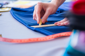 Woman tailor working on a clothing sewing stitching measuring fa