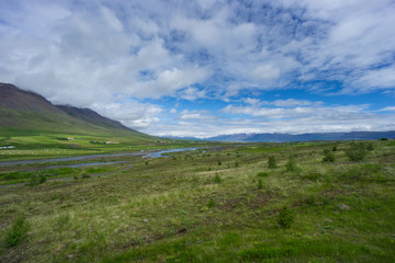 Iceland - Endless wide green valley with hundreds of hay bales in harvest time next to river