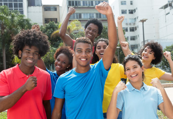 Jubelnde internationale Gruppe in bunten Shirts