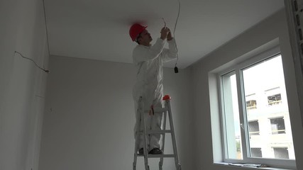 Young electrician installing smoke detector fire alarm on ceiling
