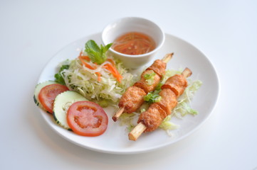Fototapeta na wymiar Shrimp on Sugarcane. A traditional Vietnamese dish. Shrimp paste wrapped around sugarcane and grilled. Served with fresh vegetable and homemade sauce.