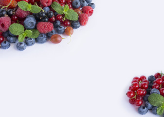 Various fresh summer berries on white background. Ripe raspberries, strawberries, blueberries, gooseberries, blackberries, blackcurrants and red currants, mint.