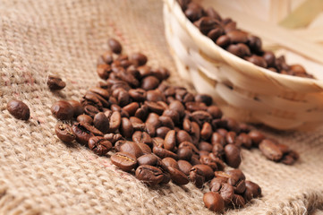 Close-up of coffee beans with a wicker basket on a burlap