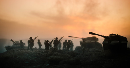 Fototapeta na wymiar War Concept. Military silhouettes fighting scene on war fog sky background, World War Soldiers Silhouettes Below Cloudy Skyline At night. Attack scene. Armored vehicles. Tanks battle