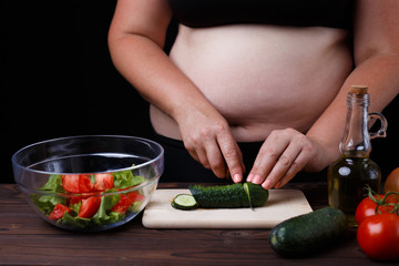 Dieting, healthy food, weight losing, well-being. Overweight fat woman slicing a cucumber for salad. Organic tasty fresh low-calorie food, cooking process