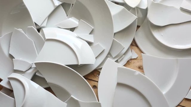 many white broken plates on a wooden floor
