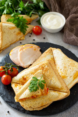 Pressed and toasted double sandwich with chicken, Korean carrots, cheese and tomatoes on a gray stone or slate.