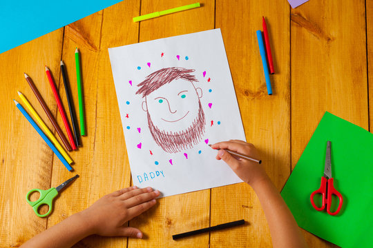 Child draws a portrait of his dad on father's day. The little boy did the drawing with pencil and marker.