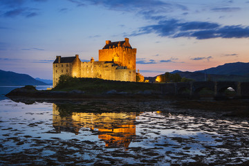 Naklejka na ściany i meble Eilean Donan Castle at Kyle reflecting itself into the water of Loch Duich and loch Alsh, during evening low tide.
