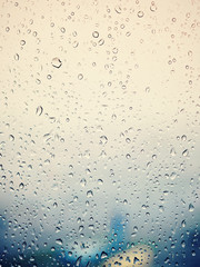 Rain in city, water drops on wet window glass, sunset