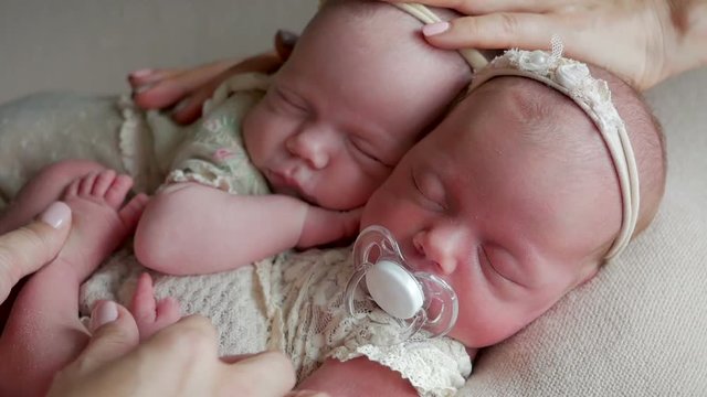 twin babies sleep in the crib in dresses and headband