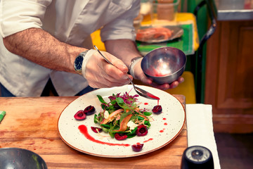 Chef is pouring sauce on vegetable appetizer, toned