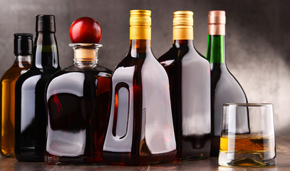 Glass and bottles of assorted alcoholic beverages.