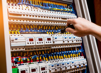 The man is repairing the switchboard voltage with automatic switches.
