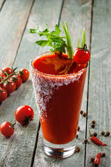 Classic bloody mary in a glass on a wooden table. Alcoholic drink made of tomato juice, vodka, pepper, salt, lemon juice, celery and other flavorings. © Maxim Khytra