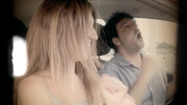 Fake 8mm amateur film: a man and a woman inside a car, doing a crazy happiness dance.
