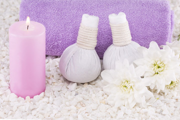Spa. Still life. Candle of pink color, a towel and white flowers on a background of white pebbles