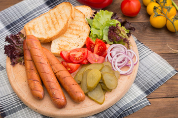 Food set for hot dog, sausage, canned cucumbers, lettuce leaves, tomatoes, onions, croutons on the wooden background. Close-up. Top view
