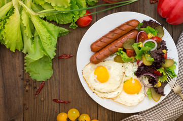 English breakfast - toast, egg, sausages and vegetables salad. Wooden rustic background. Close-up. Top view