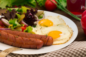 English breakfast - toast, egg, sausages and vegetables salad. Wooden rustic background. Close-up. Top view