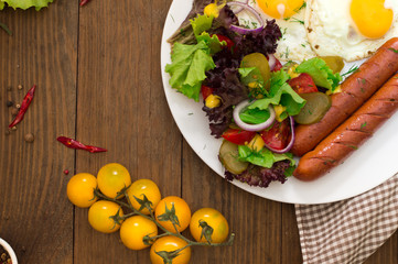 English breakfast - toast, egg, sausages and vegetables salad. Wooden rustic background. Close-up. Top view