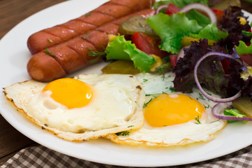 English breakfast - toast, egg, sausages and vegetables salad. Wooden rustic background. Close-up. Top view