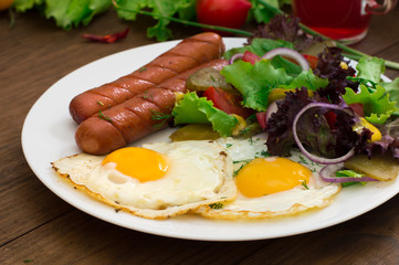 English breakfast - toast, egg, sausages and vegetables salad. Wooden rustic background. Close-up. Top view