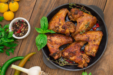 Baked chicken wings in baking pan. Selective focus. Wooden background. Close-up. Top view