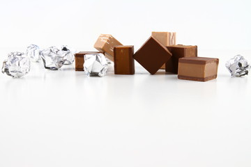 ISOLATED CHOCOLATE CUBIC WITH TINFOIL ON WHITE BACKGROUND. DESSERT STILL LIFE