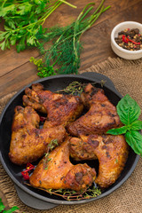 Baked chicken wings in baking pan. Selective focus. Wooden background. Close-up. Top view