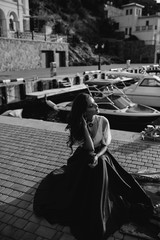 Fototapeta na wymiar Beautiful girl walking on the pier by the sea near the yacht, boats in the blue long dress