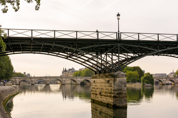 Romantic view of the Pont des Arts crossing the river Seine in the center of Paris, by a calm and peaceful morning, with the Pont Neuf and Ile de la Cite in the background.