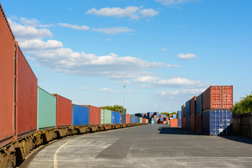 A freight train loaded with cargo containers stationing in a rail terminal.