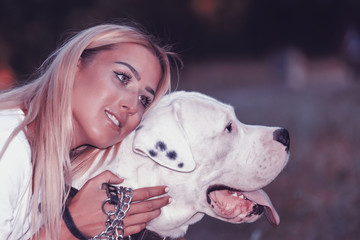 Beautiful young woman enjoys her dog in the park -  Dogo Argentino