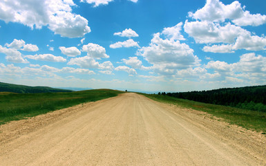 Dirt road under bright blue sky with beautiful white clouds