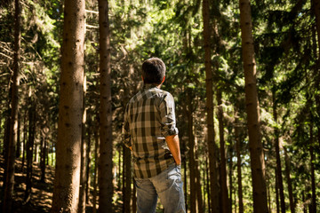 Active young adult man enjoy standing in wild pine forest on mountain in sunny summer day outdoor