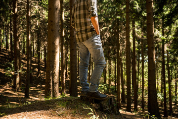 Active young adult man enjoy standing in wild pine forest on mountain in sunny summer day outdoor
