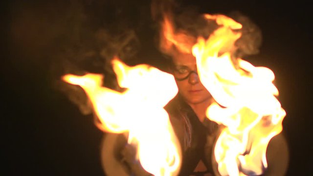 Young girl with beautiful eyes dances with burning bowls