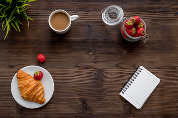 Light summer lunch. Coffee, strawberry, croissant on wooden background top view copyspace