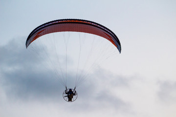 A man is flying on a paraglider over the sea and the beach