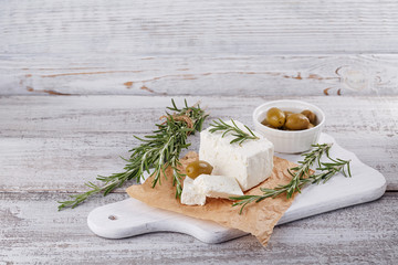 Fresh feta cheese with rosemary on white wooden serving board