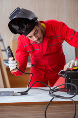 Young repairman with a welding gun electrode and a helmet weldin