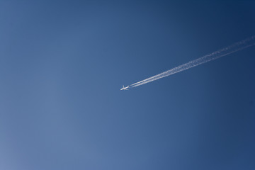 Airplane flying high in the sky with vapor trails