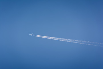 airplane flying high in the sky with vapor trails