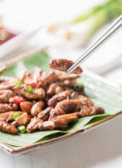 fried larva on chopsticks, edible insect eating