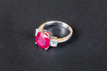 Closeup of diamind ring with ruby gem on black background