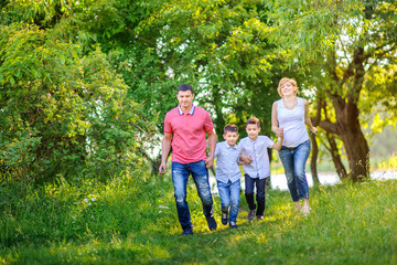 Fototapeta premium Happy family rest on the nature in the park, held together by the hands and having fun