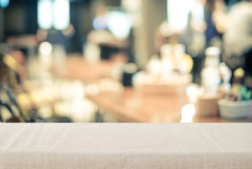 Empty tabletop with linen tablecloth over blurred cafe with bokeh background, copy space for food and product display montage background